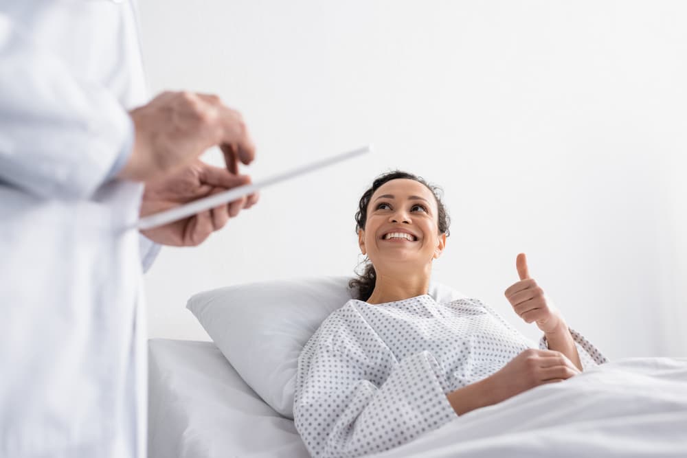 Woman on surgery bed giving doctor a thumbs up